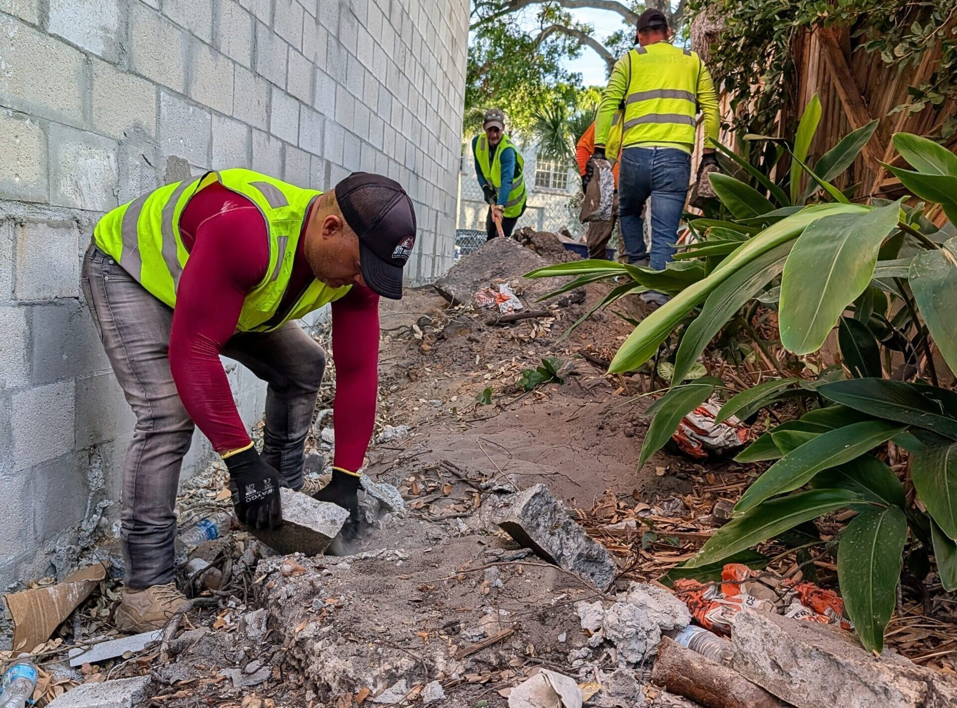 A professional cleanup crew in safety vests performing construction debris removal, clearing broken concrete and rubble from a job site tampa bay.