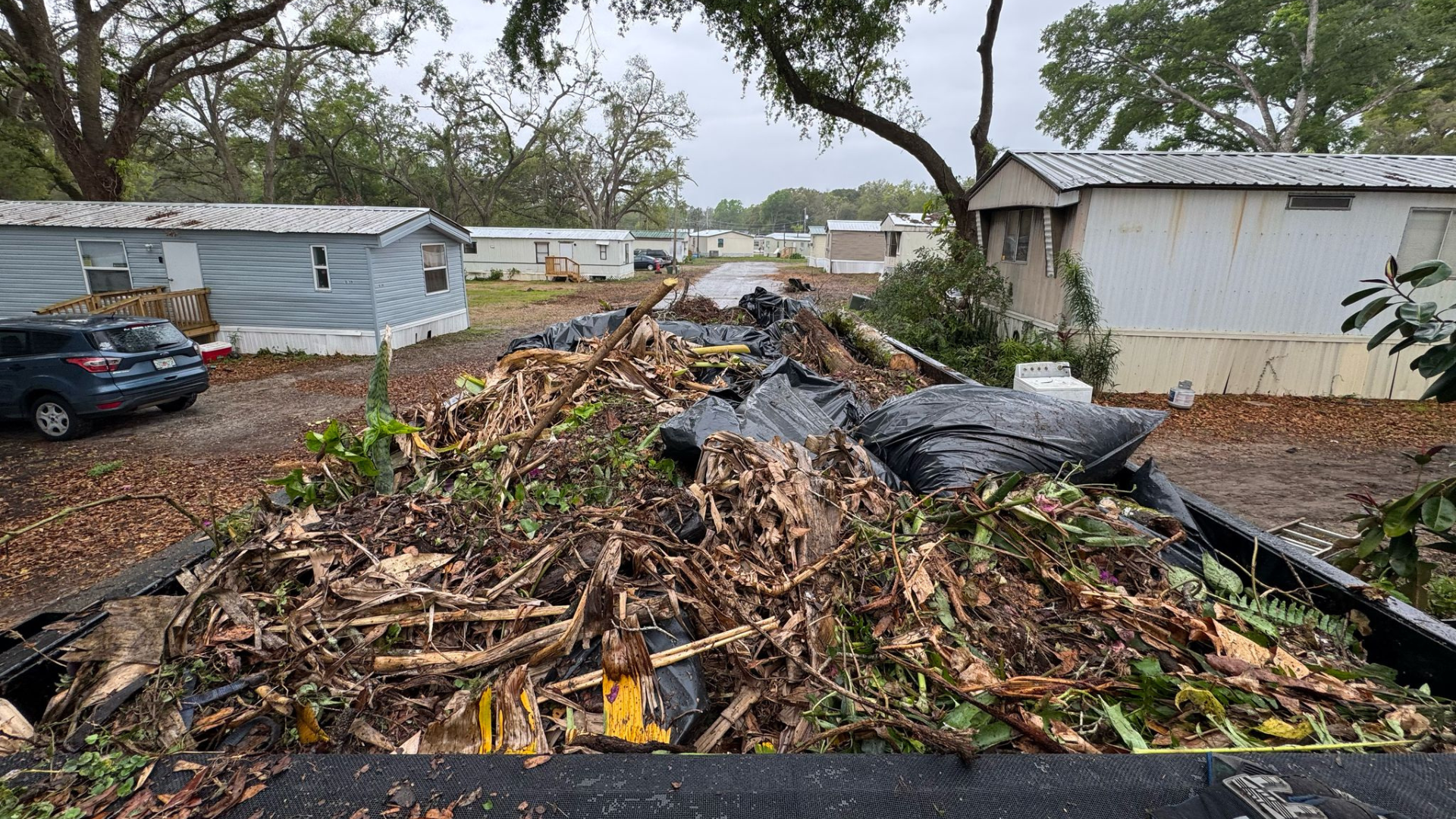 A large pile of storm debris and yard waste loaded into a large dump trailer.