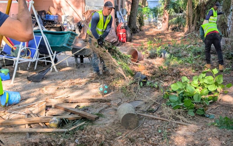 Commercial cleanup crew working outside a large property, clearing debris and performing junk removal to prepare for resale or maintenance reset