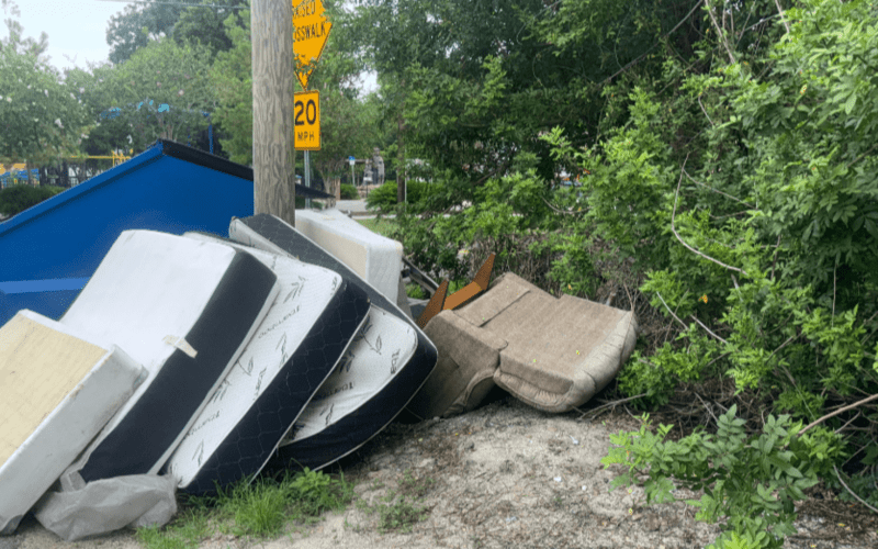 A pile of illegally dumped mattresses and furniture on a roadside in Tampa awaiting cleanup and proper junk disposal.
