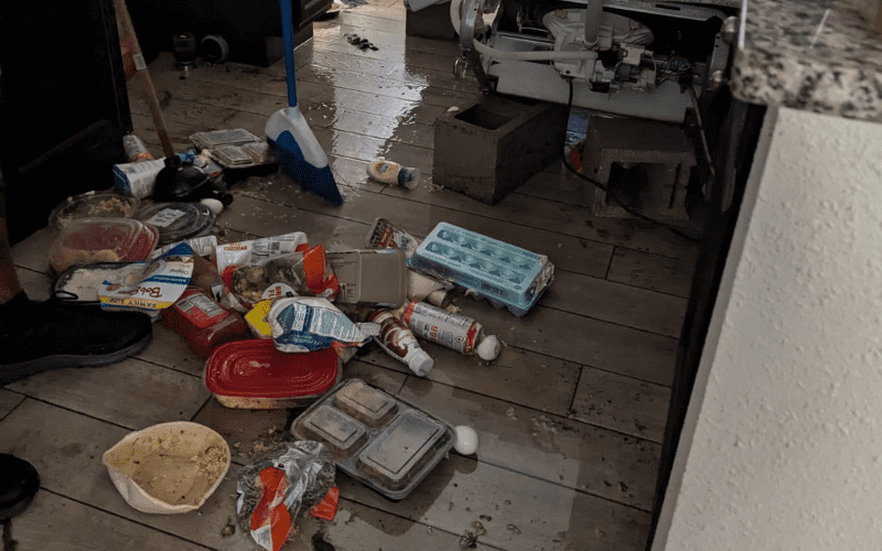 Site Masters crew member cleaning up water and debris from a kitchen flood caused by a broken appliance in a Tampa Bay home.