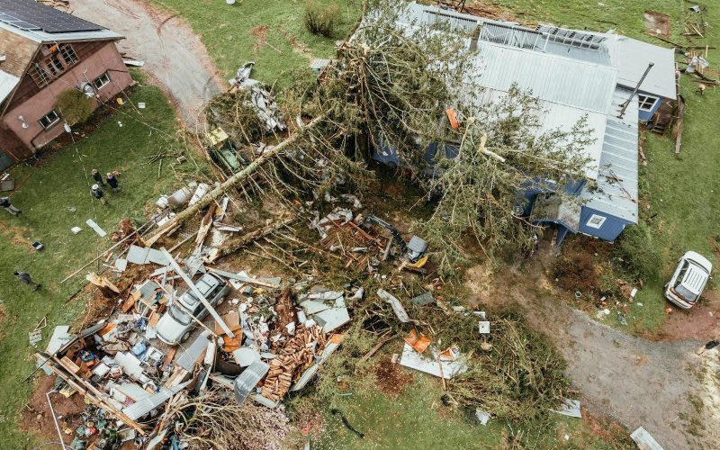 Aerial view of a property damaged by a storm, showing fallen tree limbs and widespread debris on the lawn, illustrating the urgent need for storm debris removal in Riverview