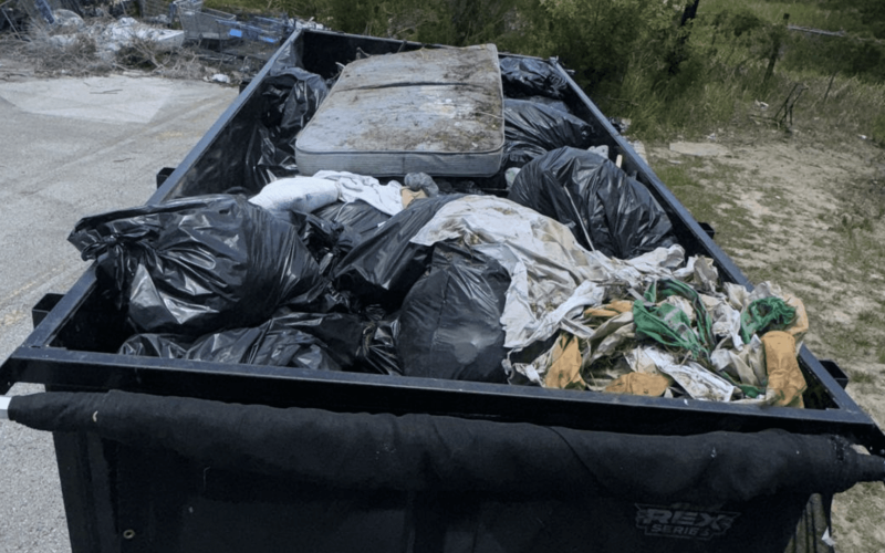 A junk removal trailer filled with trash bags and an old mattress after a property cleanup in Tampa, ready for disposal.